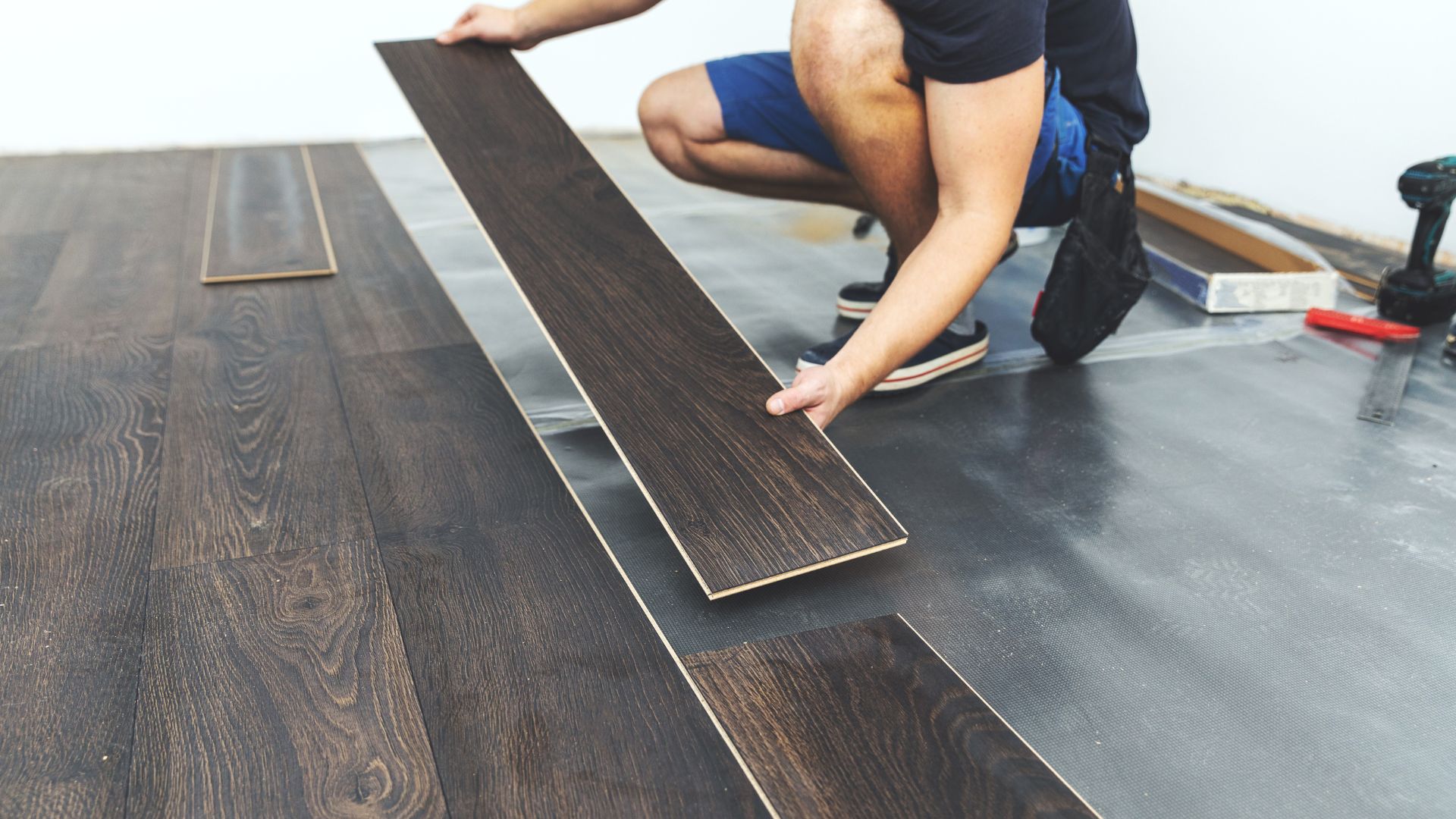 Worker installing dark wood laminate flooring panels
