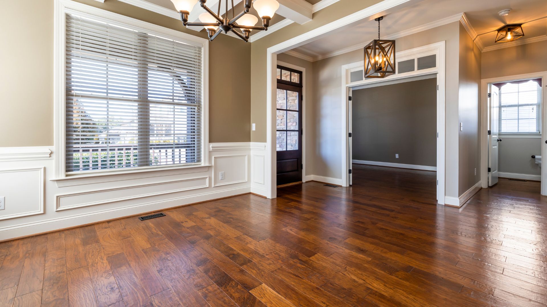 Empty room with hardwood floors, white trim, and geometric light fixtures
