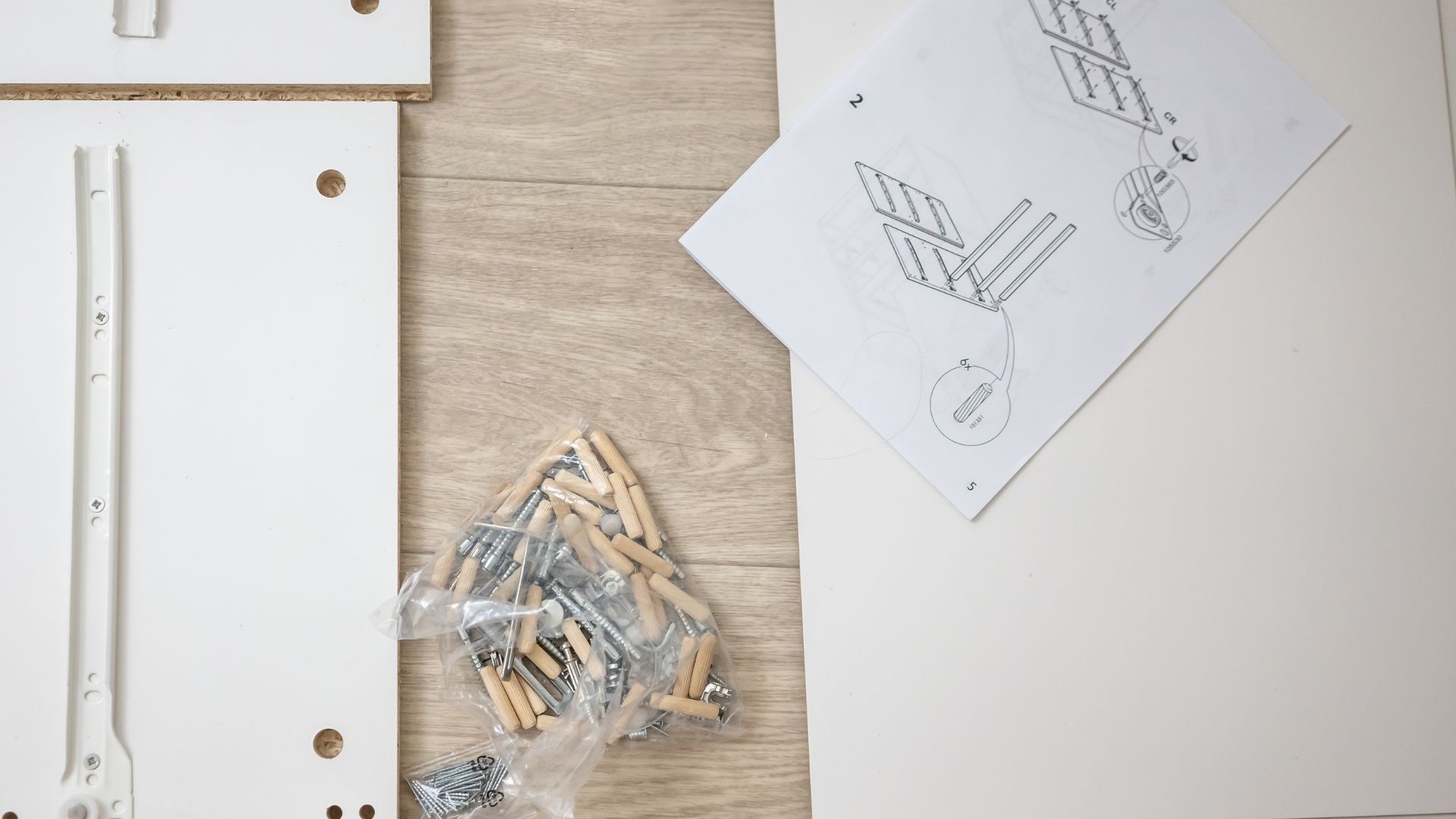 Wooden dowels, screws, and technical drawing on a wooden workshop surface