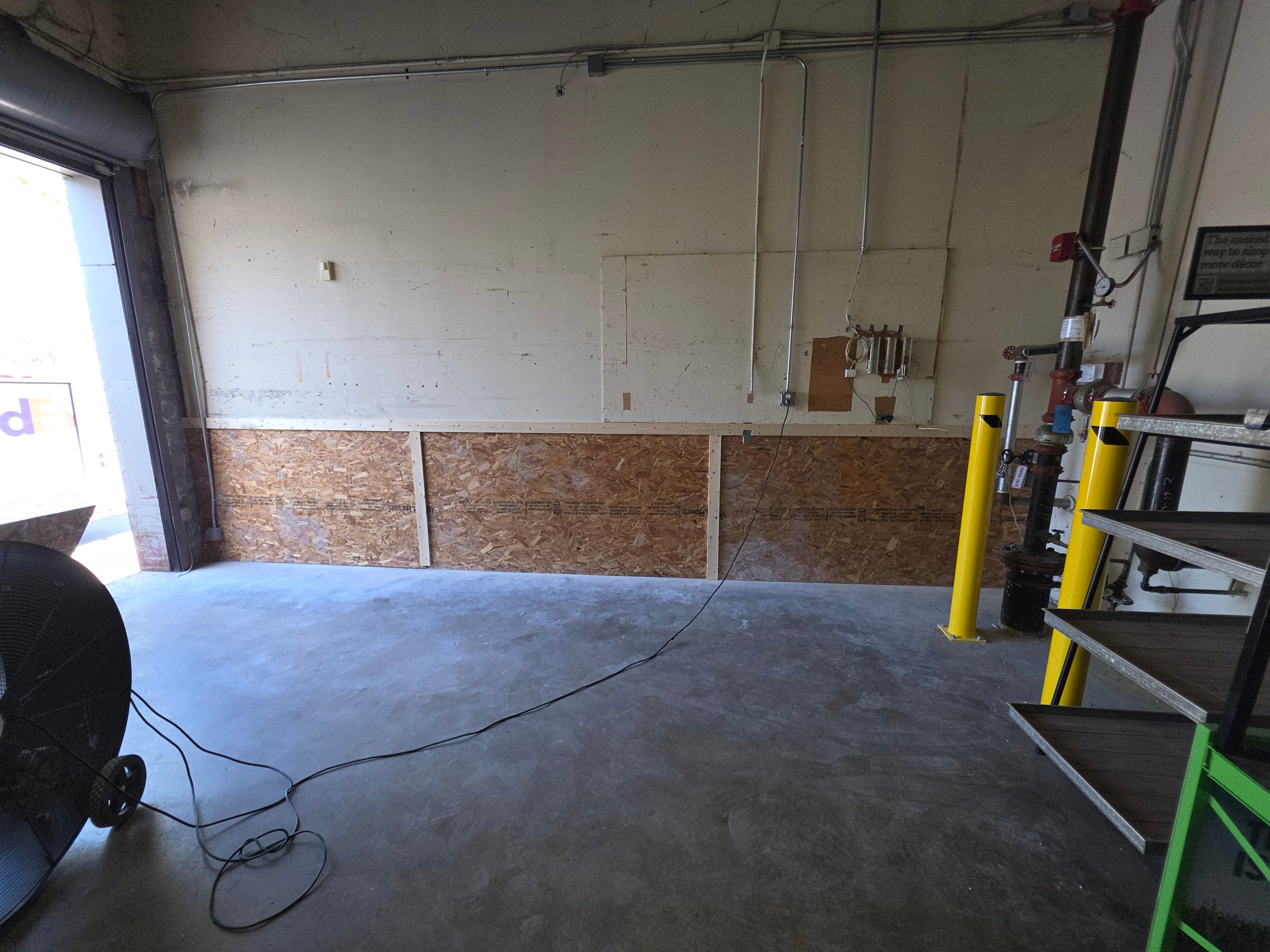 Industrial garage interior with concrete floor, OSB walls, and yellow safety poles