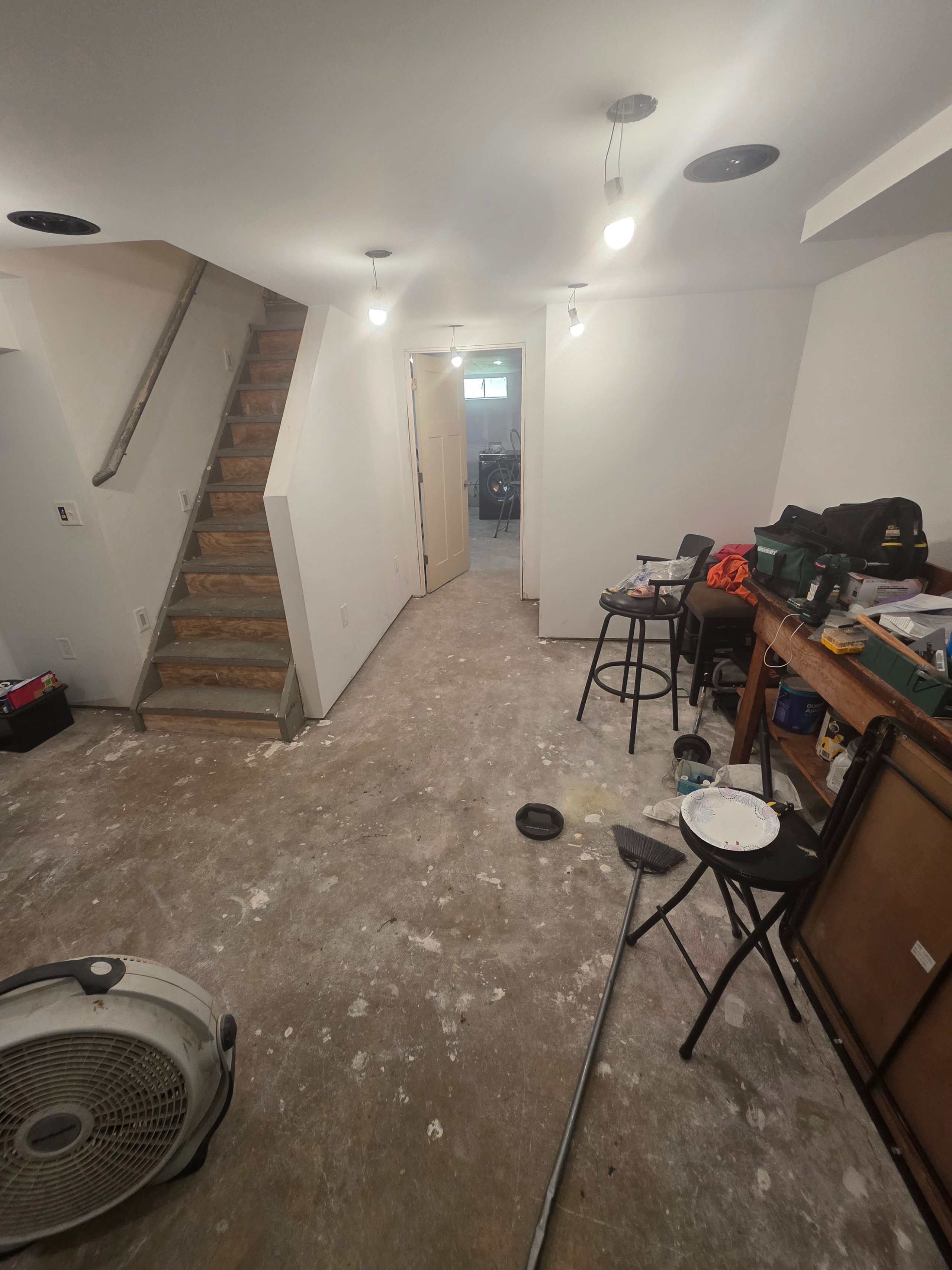 Unfinished basement with stairs, fan, and work area