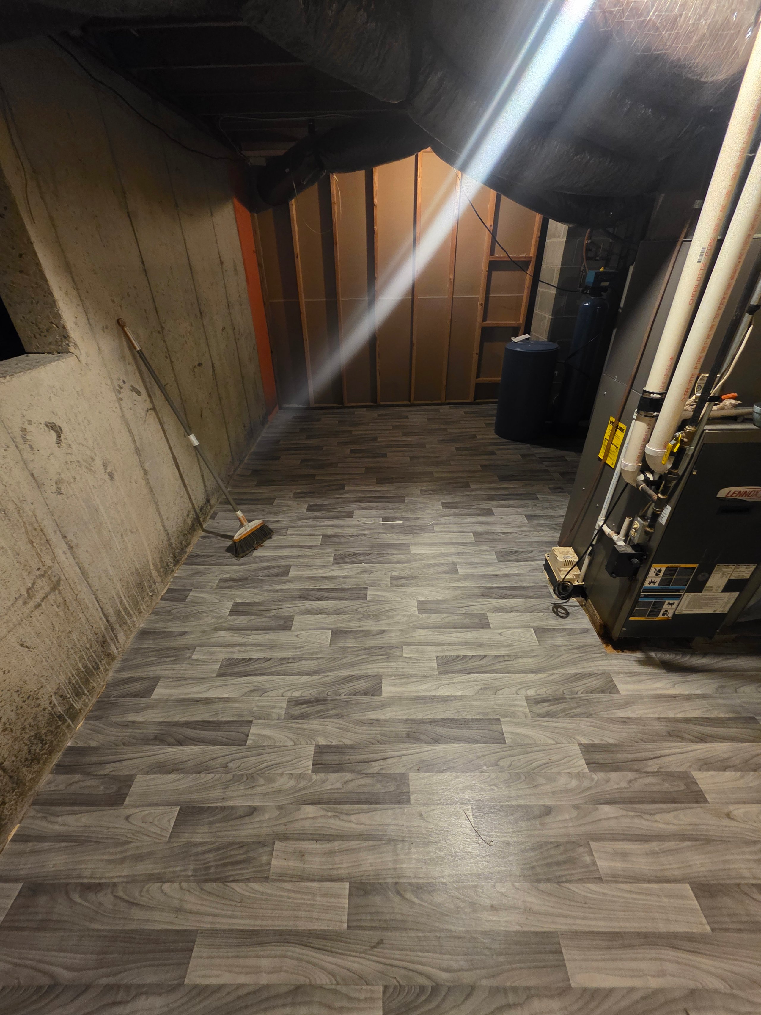 Sunlight streams into basement with new flooring, furnace, and broom