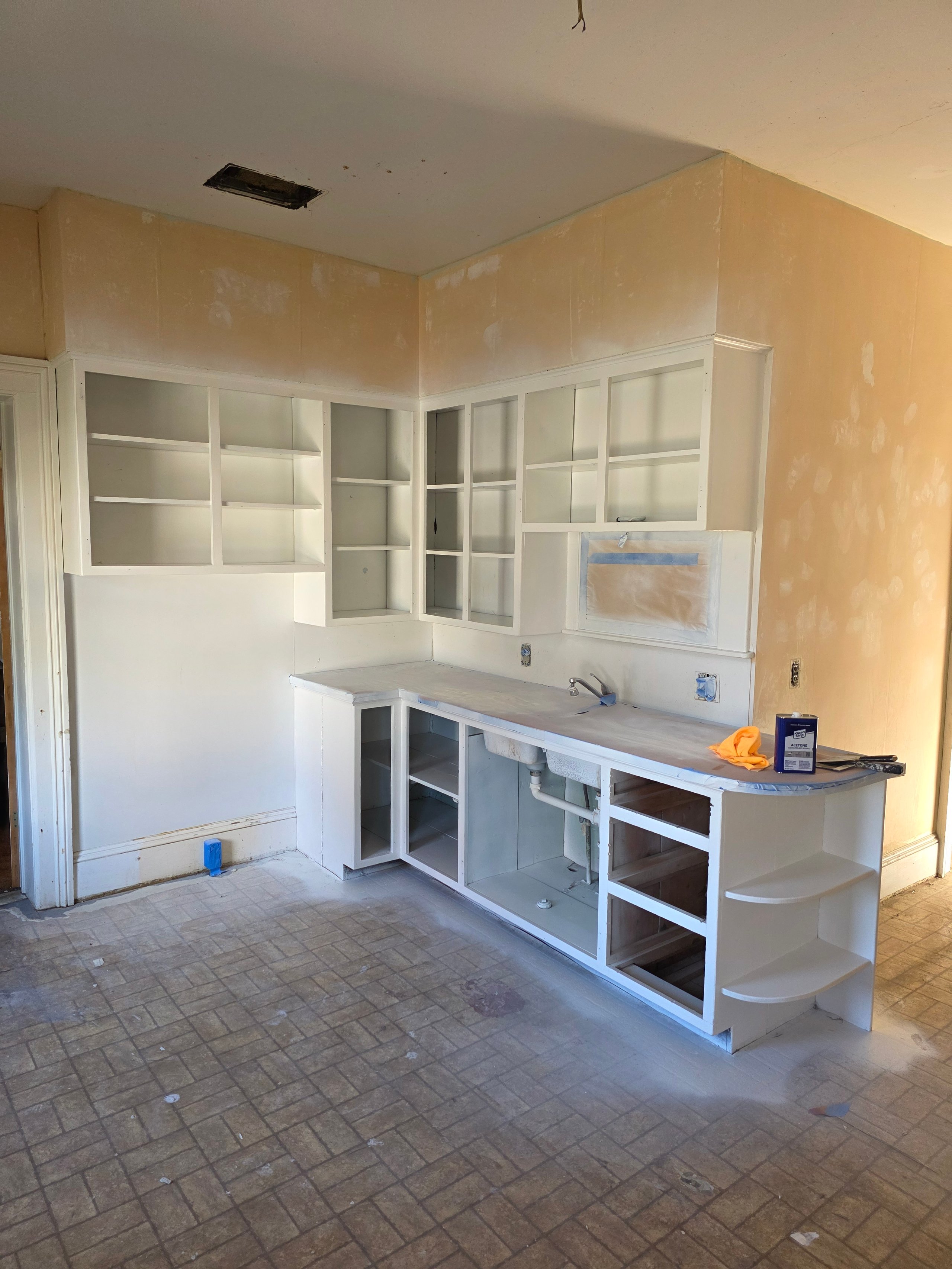 Unfinished white kitchen cabinets with open doors during renovation project
