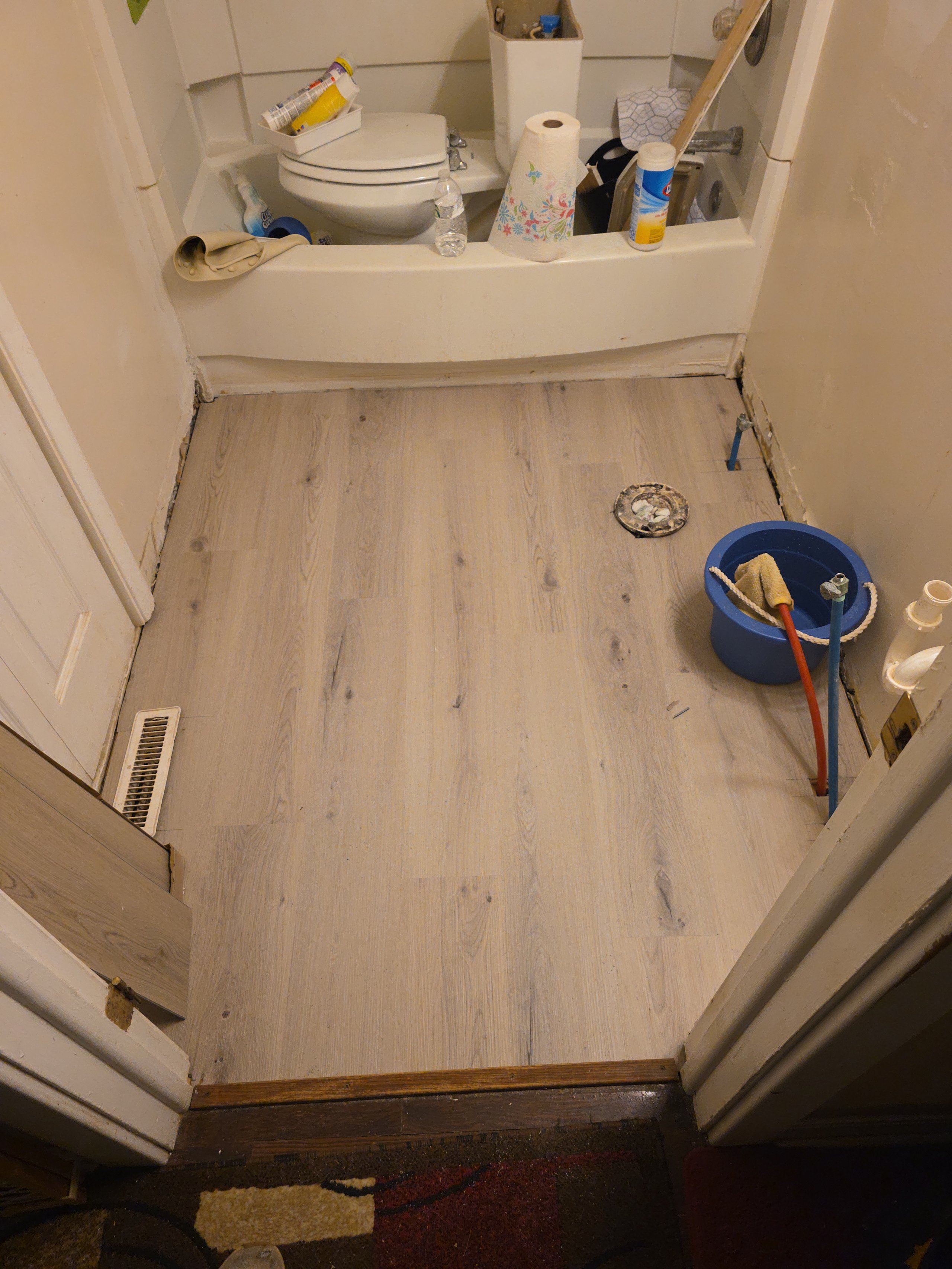 Bathroom renovation in progress with tools and new wooden floor