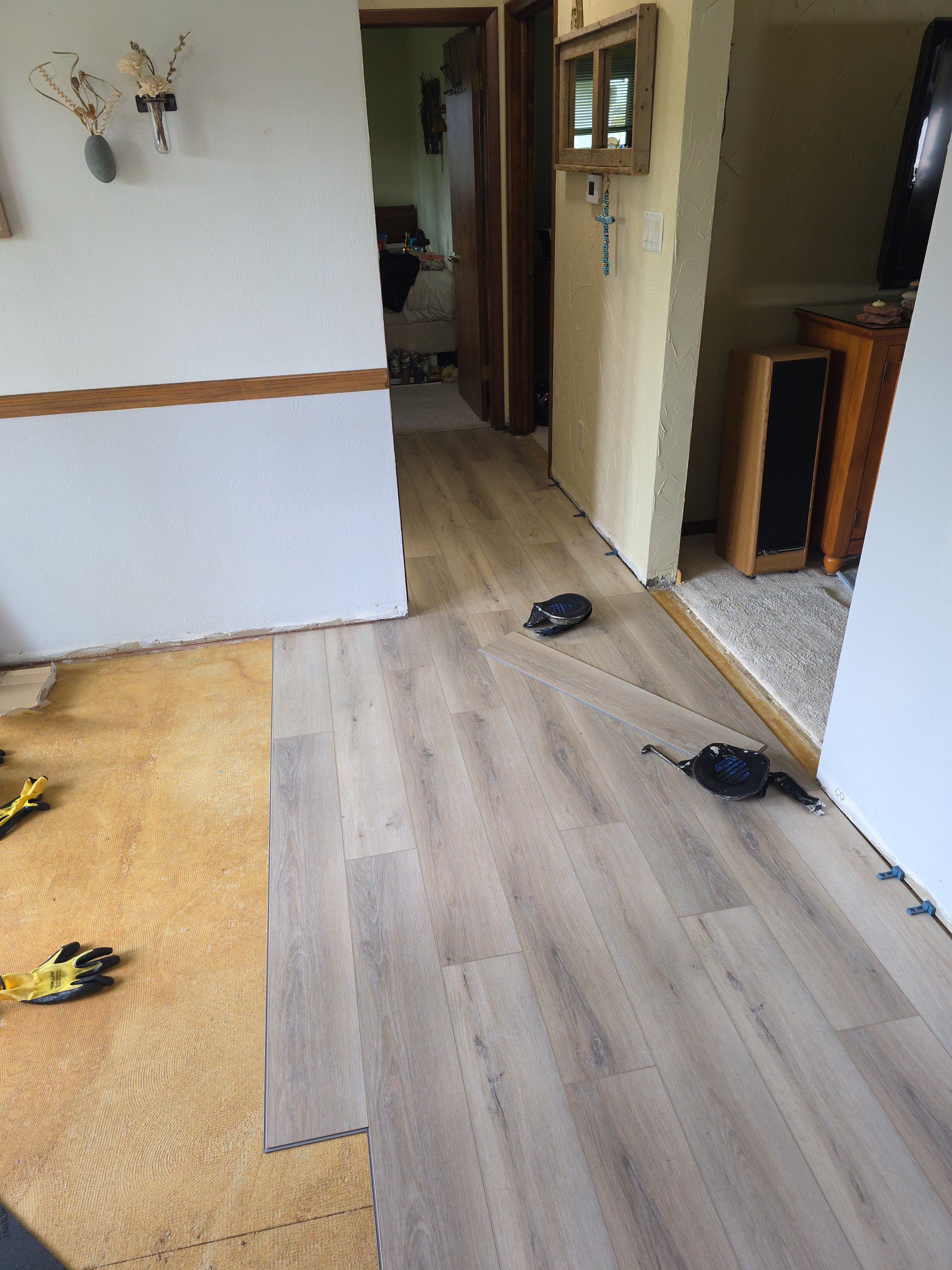 Laminate flooring installation in progress with tools and work gloves