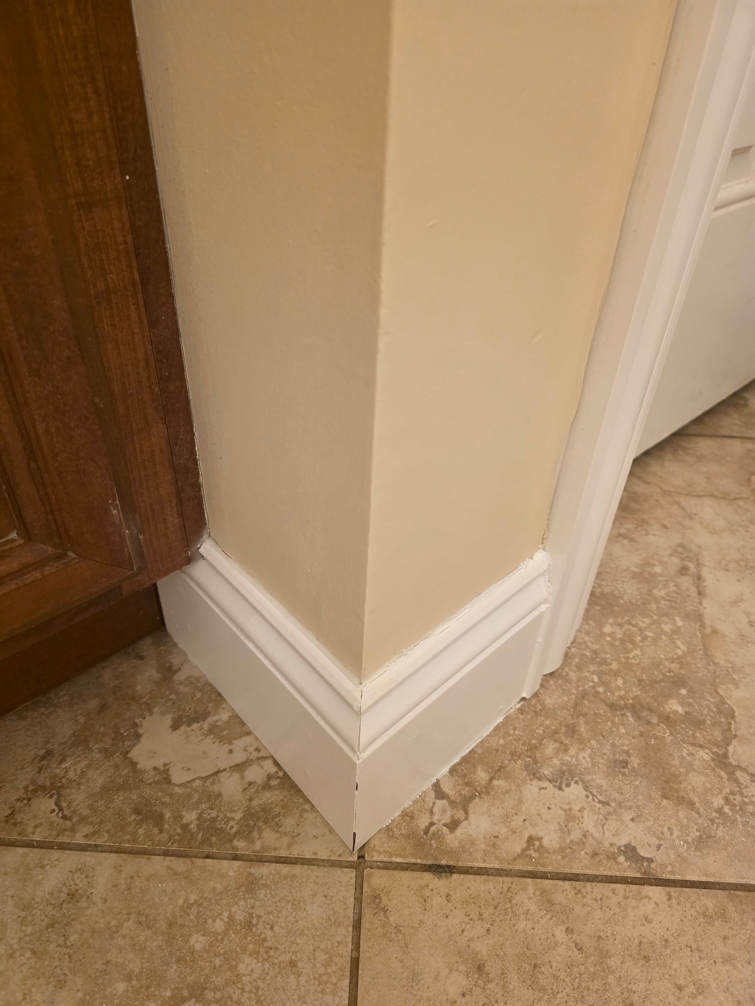 White baseboard and corner of beige wall with tile floor