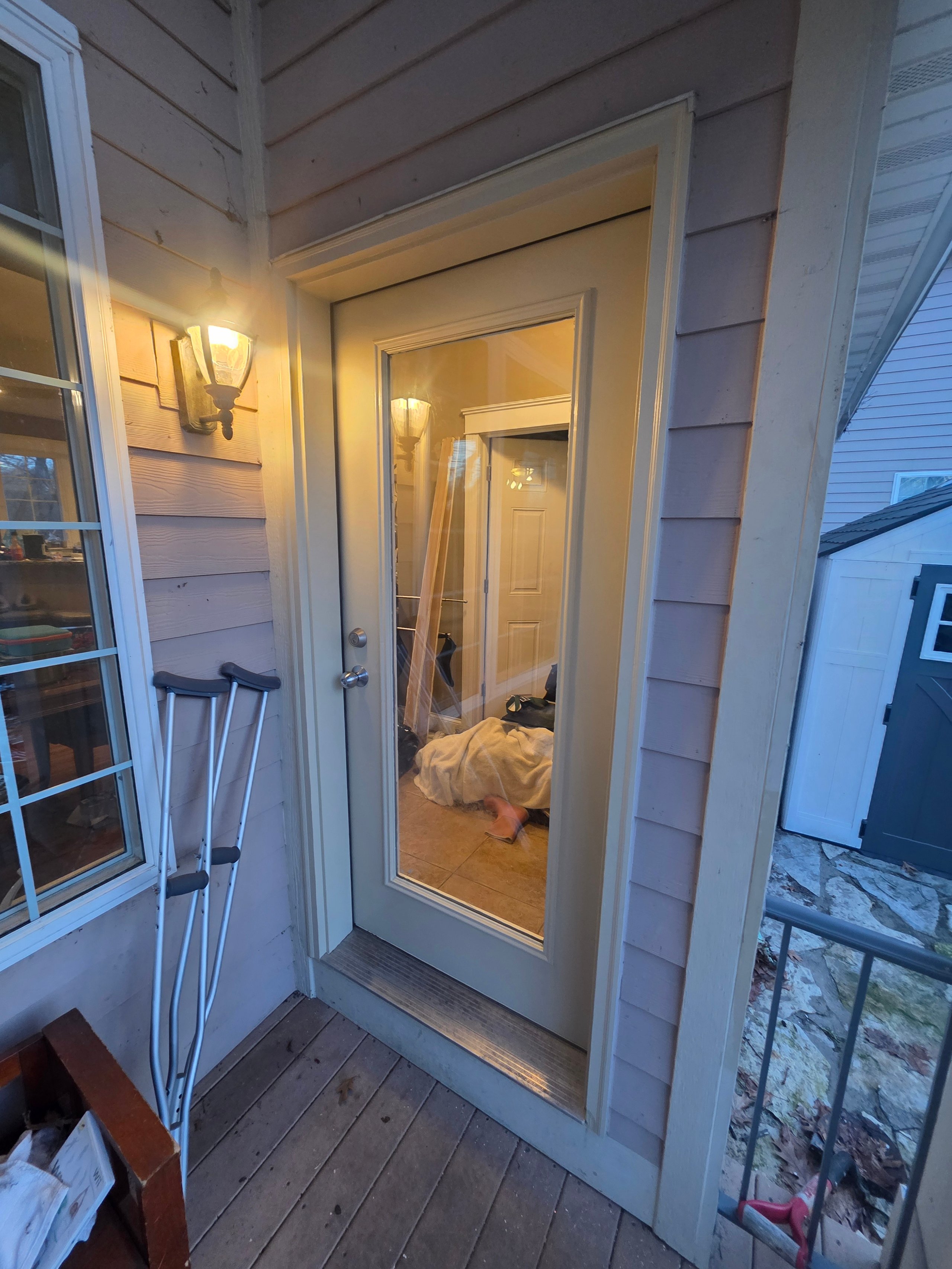 Wooden door with glass pane, crutches nearby, warm indoor light glowing