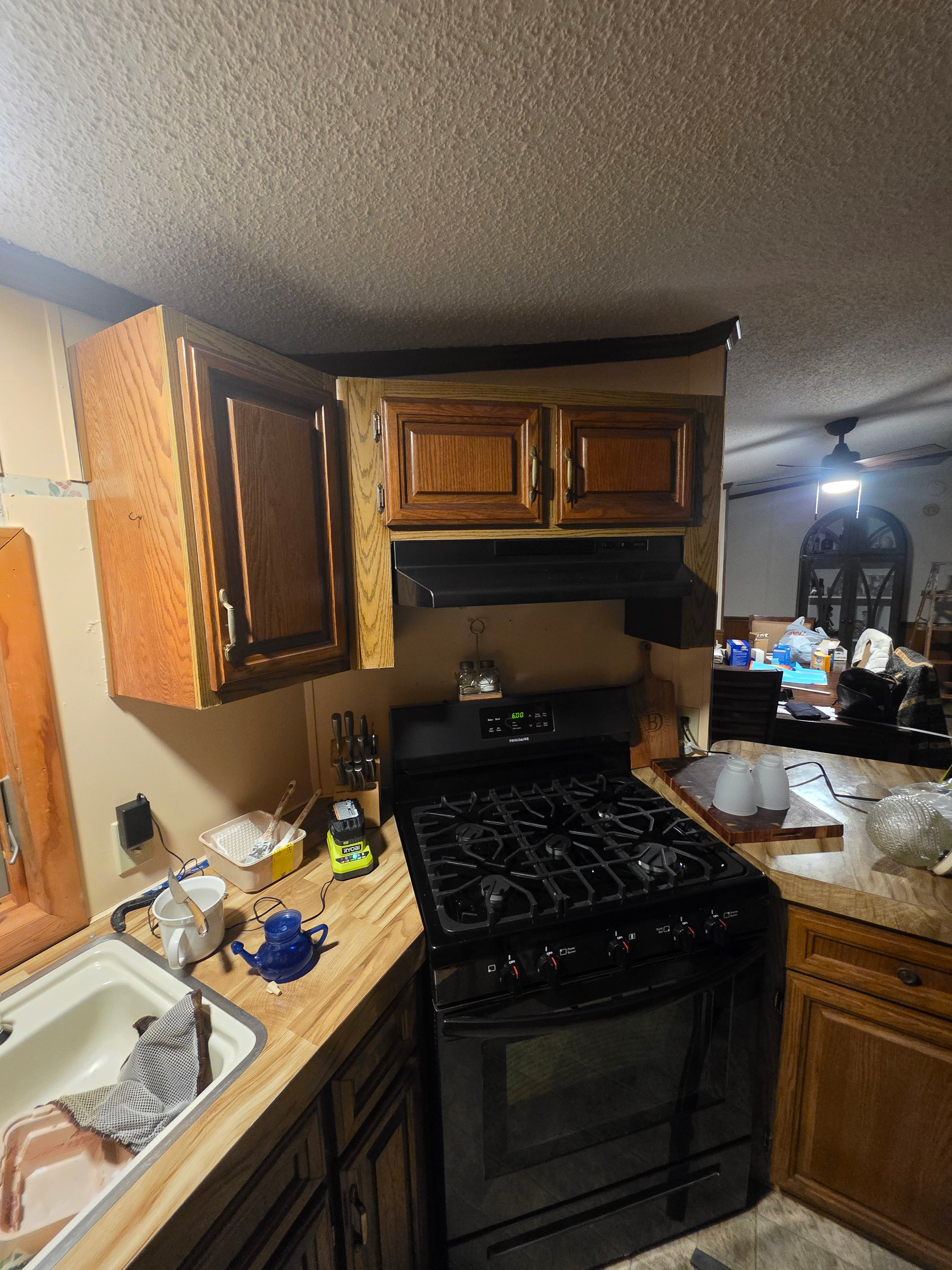 Compact kitchen with wooden cabinets, black stove, and butcher block countertop