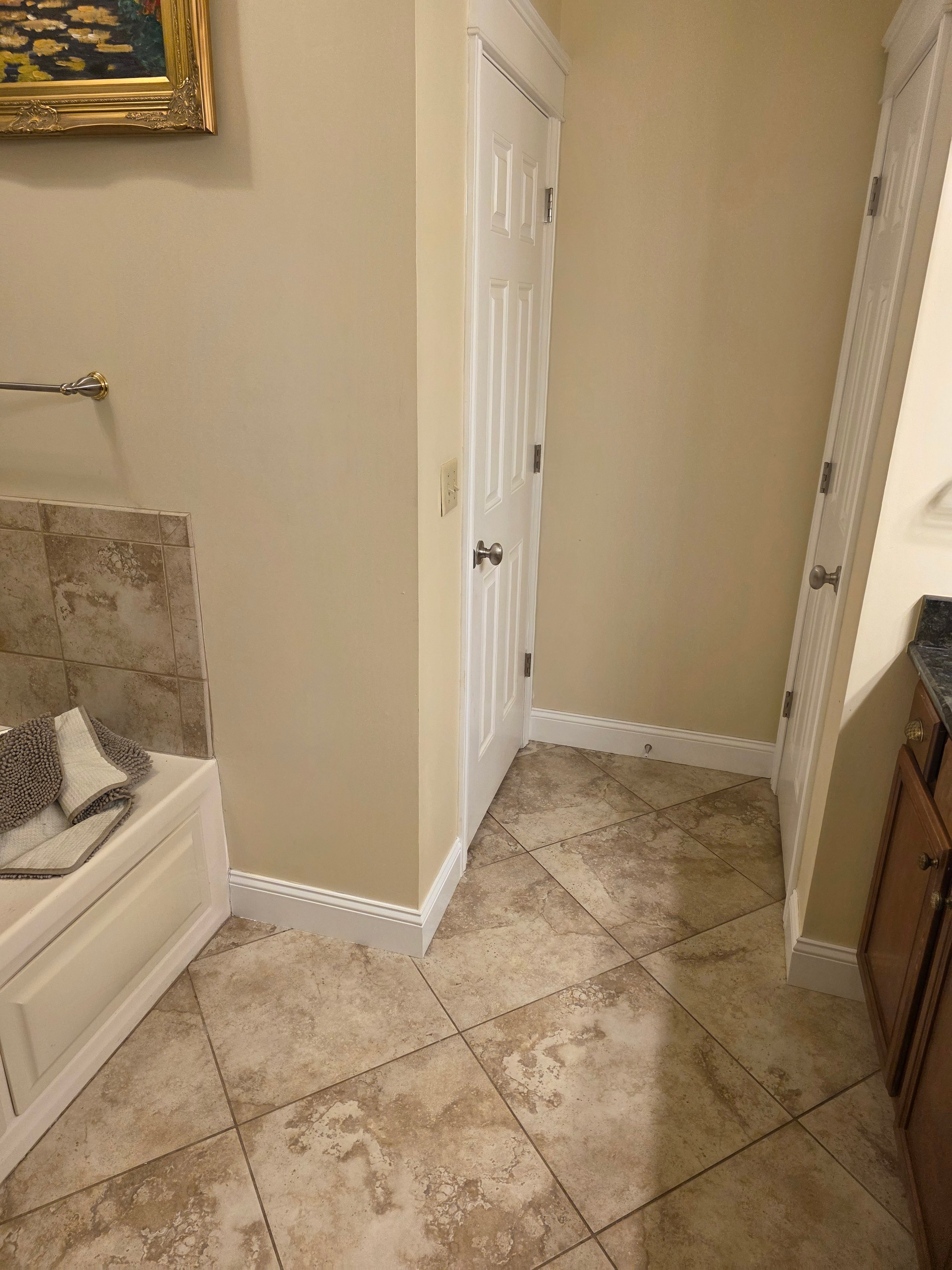 Bathroom interior with white doors, beige walls, and stone tile flooring