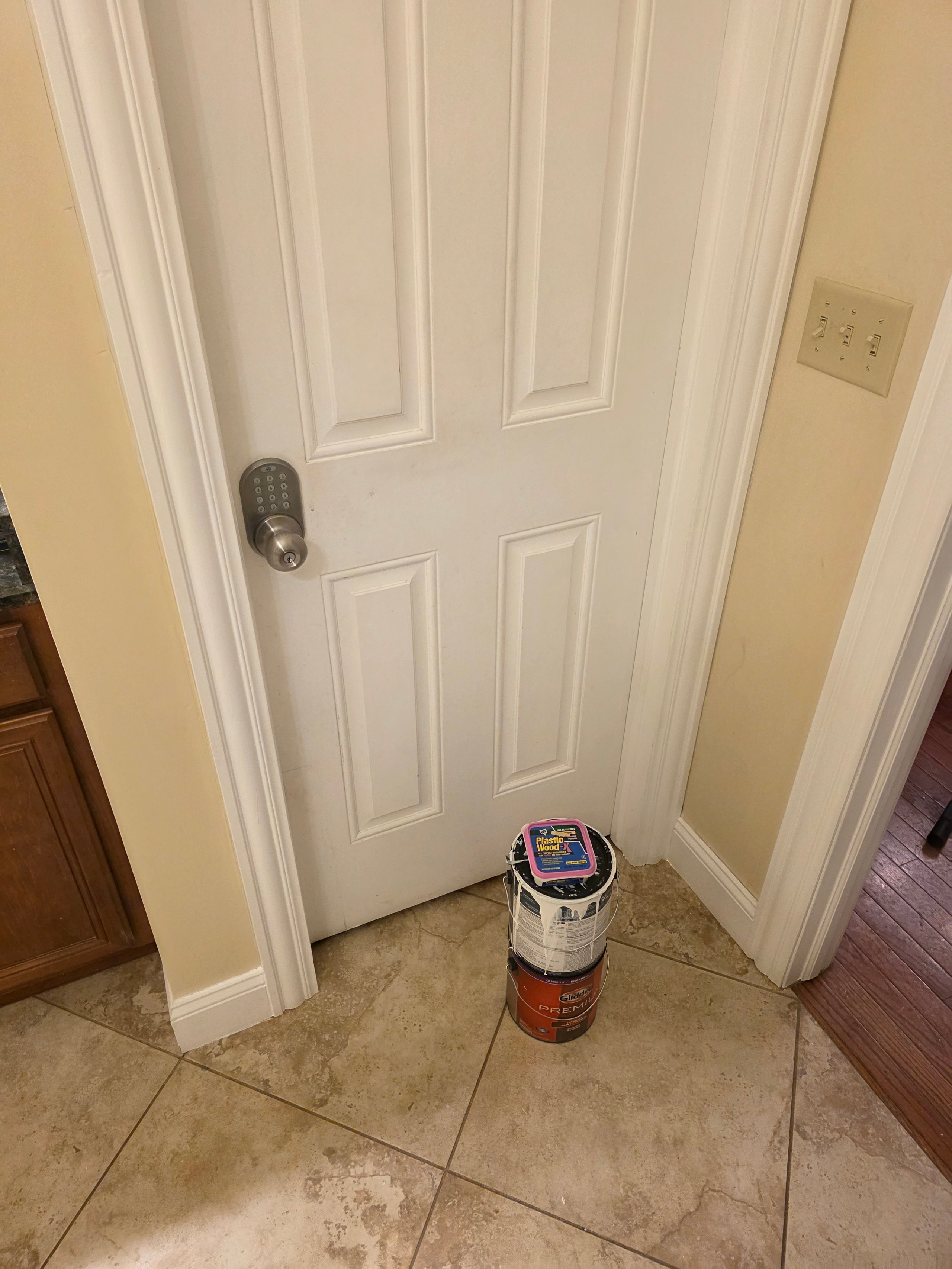 White door with electronic keypad lock and paint cans on tiled floor