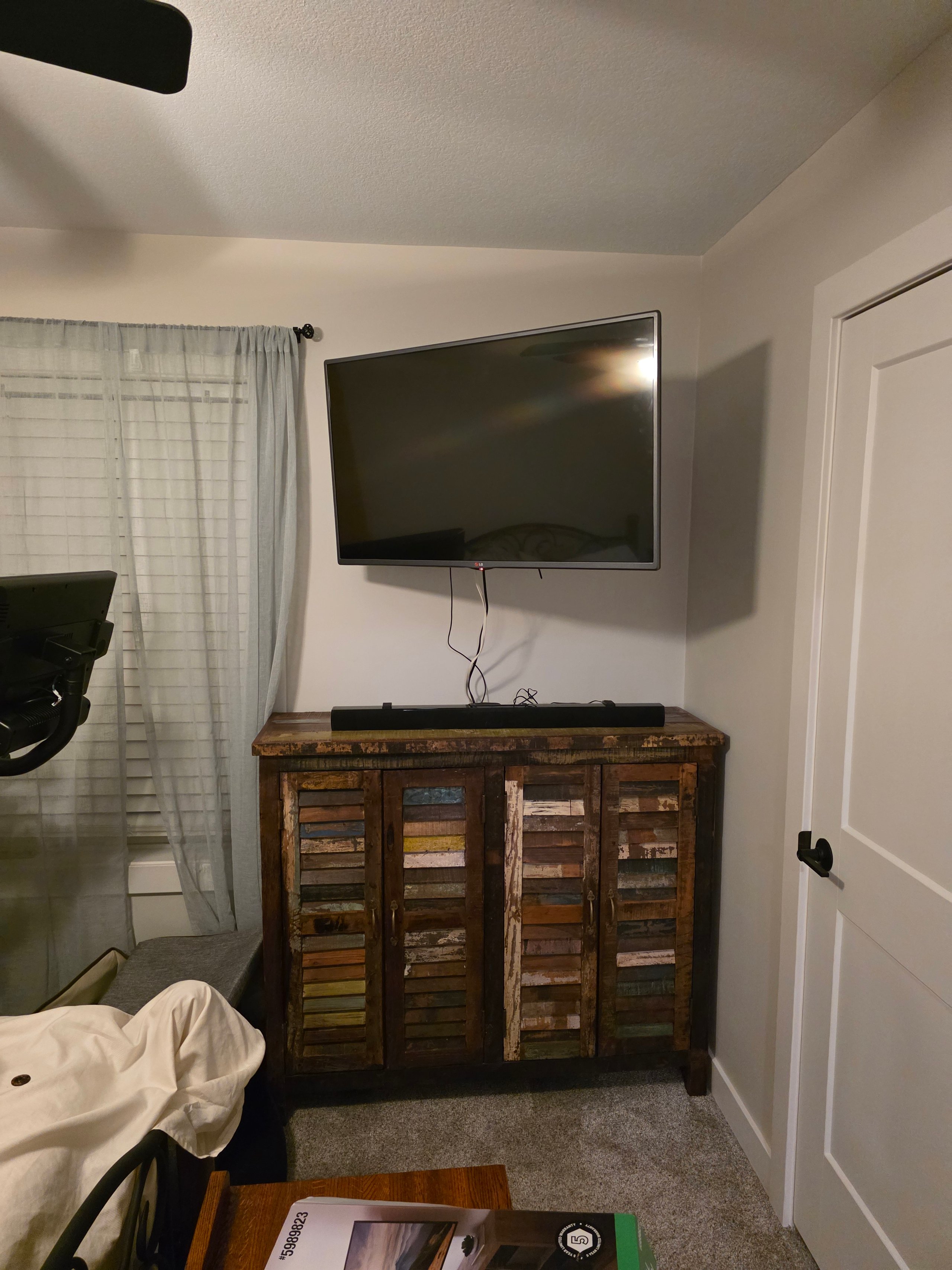 Rustic wooden cabinet under wall-mounted TV with sheer curtains